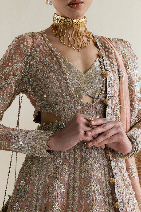 Suffuse Mahveen luxury bridal pishwas outfit front view featuring heavily hand-embellished tissue pishwas with fitted sleeves and layered bustier neckline, adorned with intricate mirror work, gota, resham and floral embroidery in sage green and gold accents, paired with richly panelled lehenga featuring ornate golden silver border detailing, completed with shikargah inspired tissue dupatta with geometric patterns, mirror work and four sided embroidered edges, premium Pakistani bridal couture