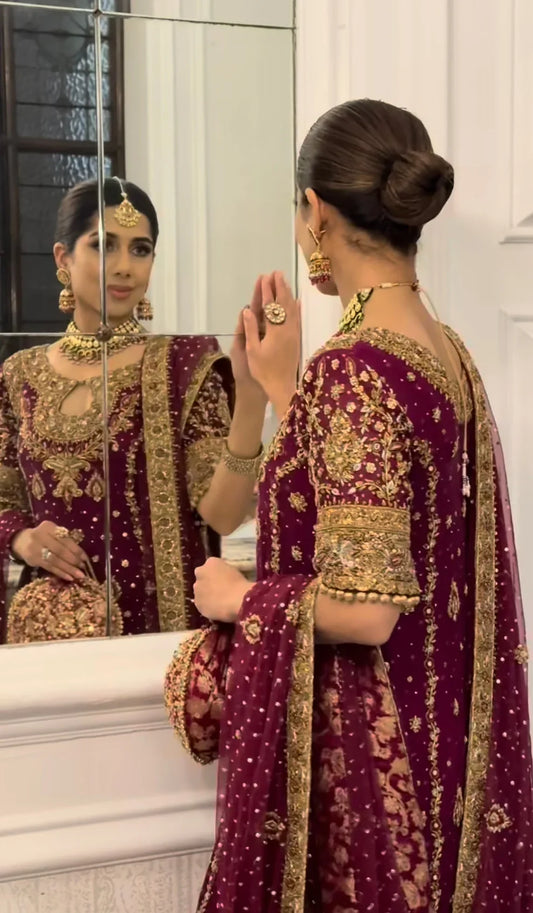 Libah by Haris Shakeel luxury formal outfit front view featuring deep maroon raw silk shirt with heavy all-over gold hand embroidery including intricate floral motifs, zari, resham and sequins work, elegant straight silhouette with richly decorated sleeves and ornate border finishing, paired with champagne toned straight trousers and sheer organza dupatta with subtle booti spray and detailed embroidered pallu, premium Pakistani designer outfit perfect for weddings, festive occasions, mehndi.