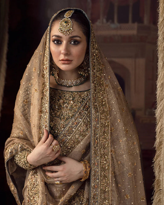 Faiza Saqlain Muntaha luxury bridal couture outfit front view featuring heavily hand-embellished raw silk shirt with intricate resham, dabka, naqshi and sequin embroidery in Mughal inspired floral motifs, paired with voluminous lehenga adorned with multiple richly embroidered borders and antique finishing, completed with a gracefully draped zari net dupatta with detailed adda work and ornate edging, premium bridal ensemble perfect for weddings, nikkah ceremonies and luxury festive occasions