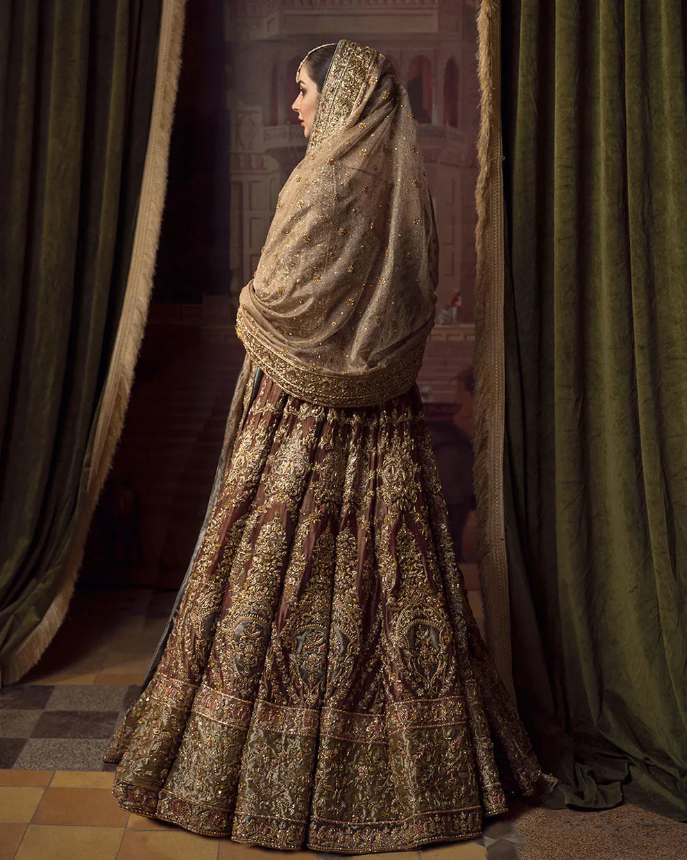 Faiza Saqlain Muntaha luxury bridal couture outfit front view featuring heavily hand-embellished raw silk shirt with intricate resham, dabka, naqshi and sequin embroidery in Mughal inspired floral motifs, paired with voluminous lehenga adorned with multiple richly embroidered borders and antique finishing, completed with a gracefully draped zari net dupatta with detailed adda work and ornate edging, premium bridal ensemble perfect for weddings, nikkah ceremonies and luxury festive occasions