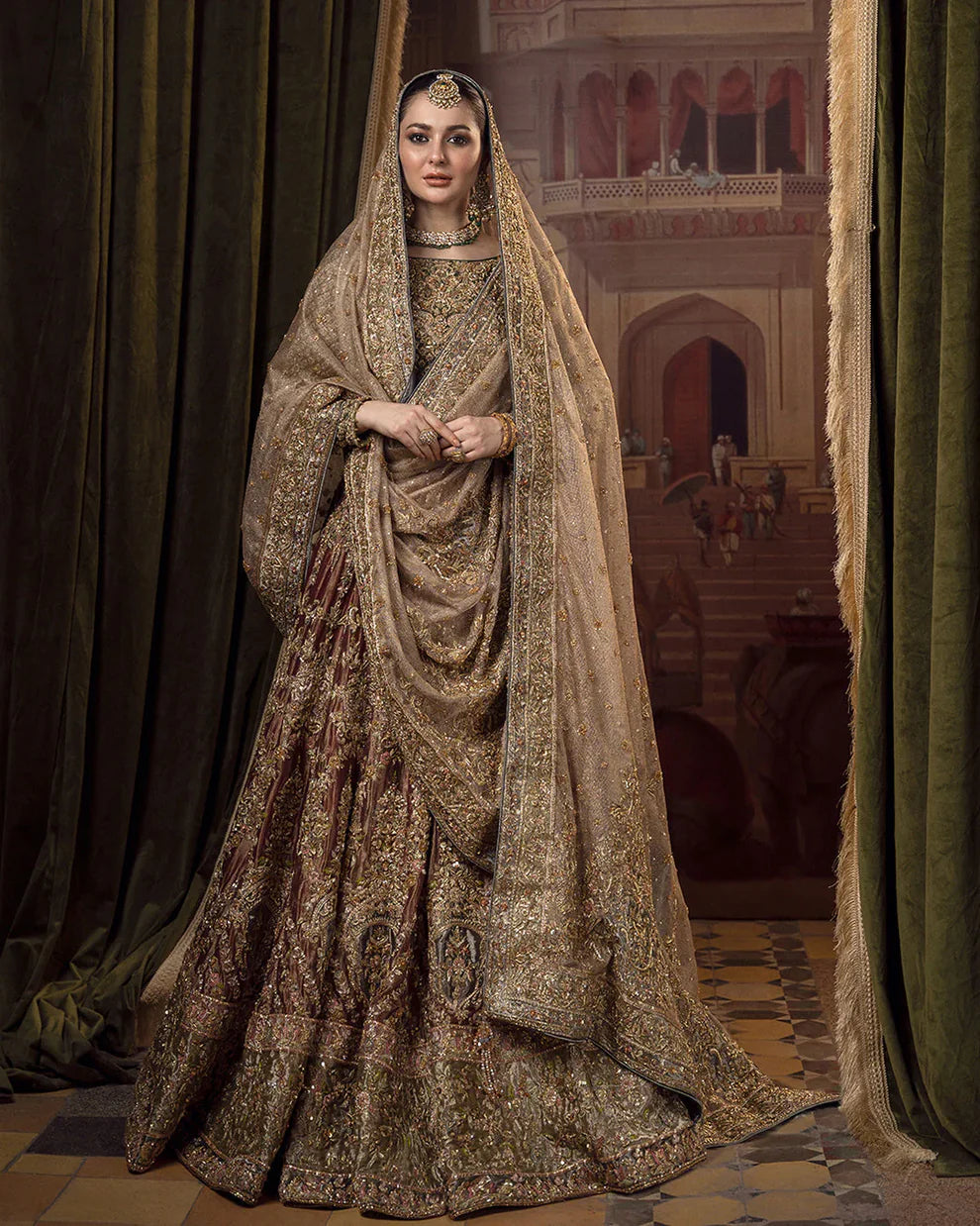 Faiza Saqlain Muntaha luxury bridal couture outfit front view featuring heavily hand-embellished raw silk shirt with intricate resham, dabka, naqshi and sequin embroidery in Mughal inspired floral motifs, paired with voluminous lehenga adorned with multiple richly embroidered borders and antique finishing, completed with a gracefully draped zari net dupatta with detailed adda work and ornate edging, premium bridal ensemble perfect for weddings, nikkah ceremonies and luxury festive occasions