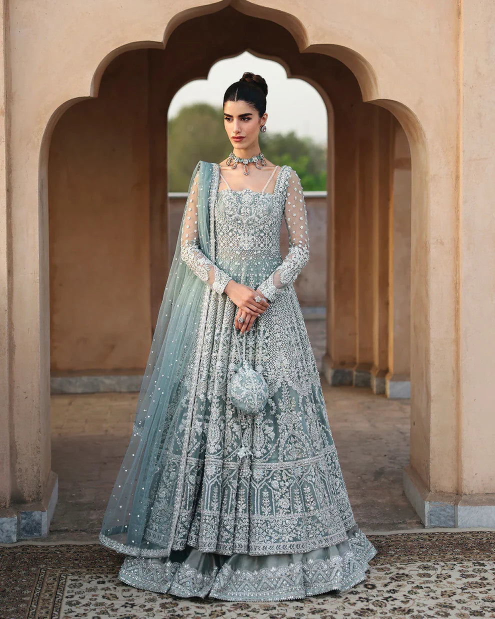 Dorien by Faiza Saqlain luxury mint blue bridal couture outfit front view featuring heavily hand-embellished net pishwas with intricate sequins, stones and resham embroidery in delicate floral heritage patterns, elegantly structured bodice with fitted sleeves and flowing flare silhouette, paired with richly embellished tissue lehenga featuring ornate embroidered borders and layered detailing, completed with heavily decorated net dupatta with all over sequin spray and four sided embroidered edging.