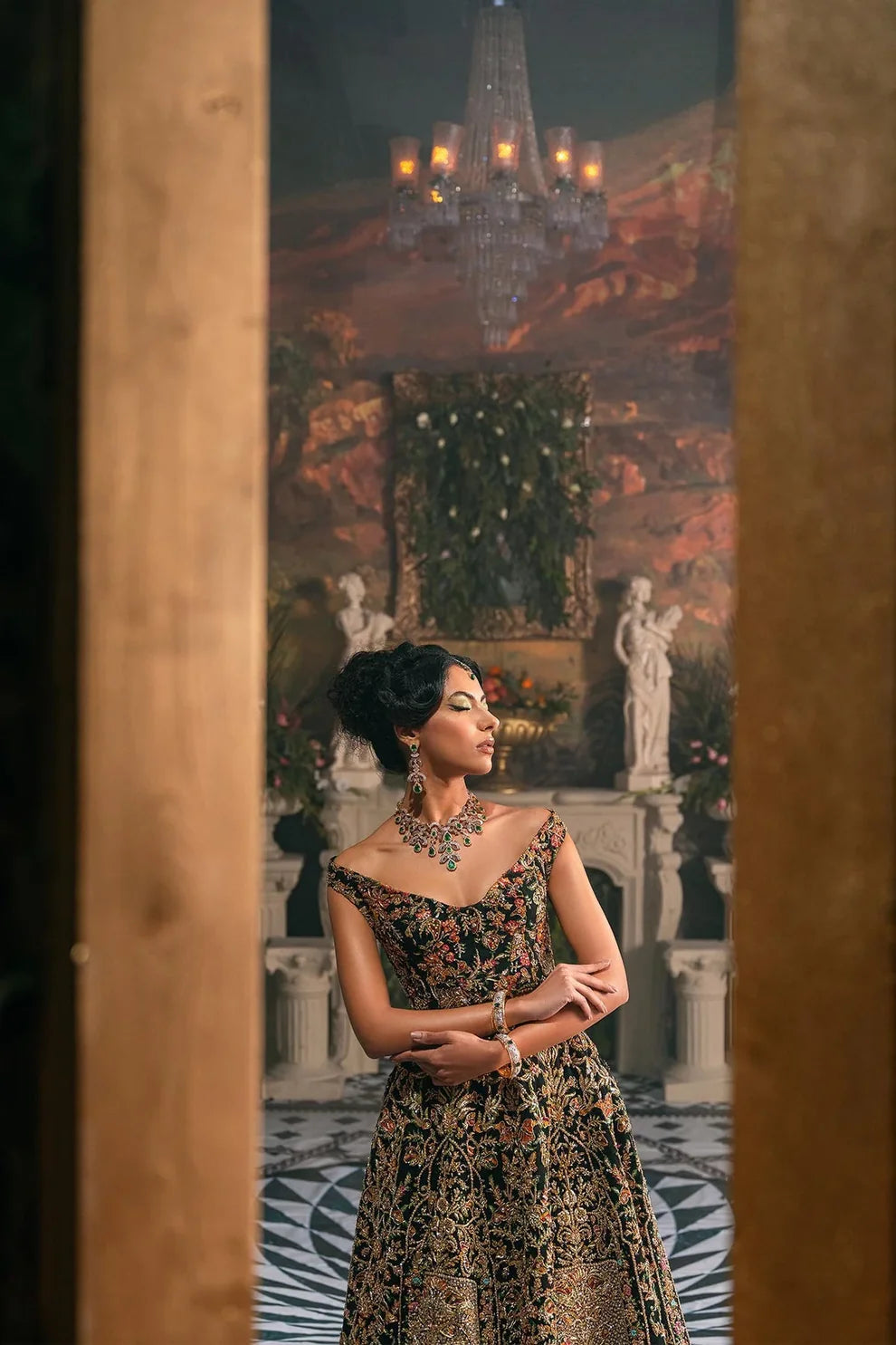 Ajooba by Fahad Hussayn luxury black bridal couture outfit front view featuring heavily hand-embellished net lehenga and blouse with intricate resham, zardozi, naqshi, dabka and crystal embroidery forming rich floral Mughal inspired patterns, dramatic structured silhouette with full flare lehenga and detailed choli, paired with sheer organza dupatta scattered with delicate floral motifs and ornate embroidered border finishing, premium high-end bridal ensemble perfect for weddings, receptions etc