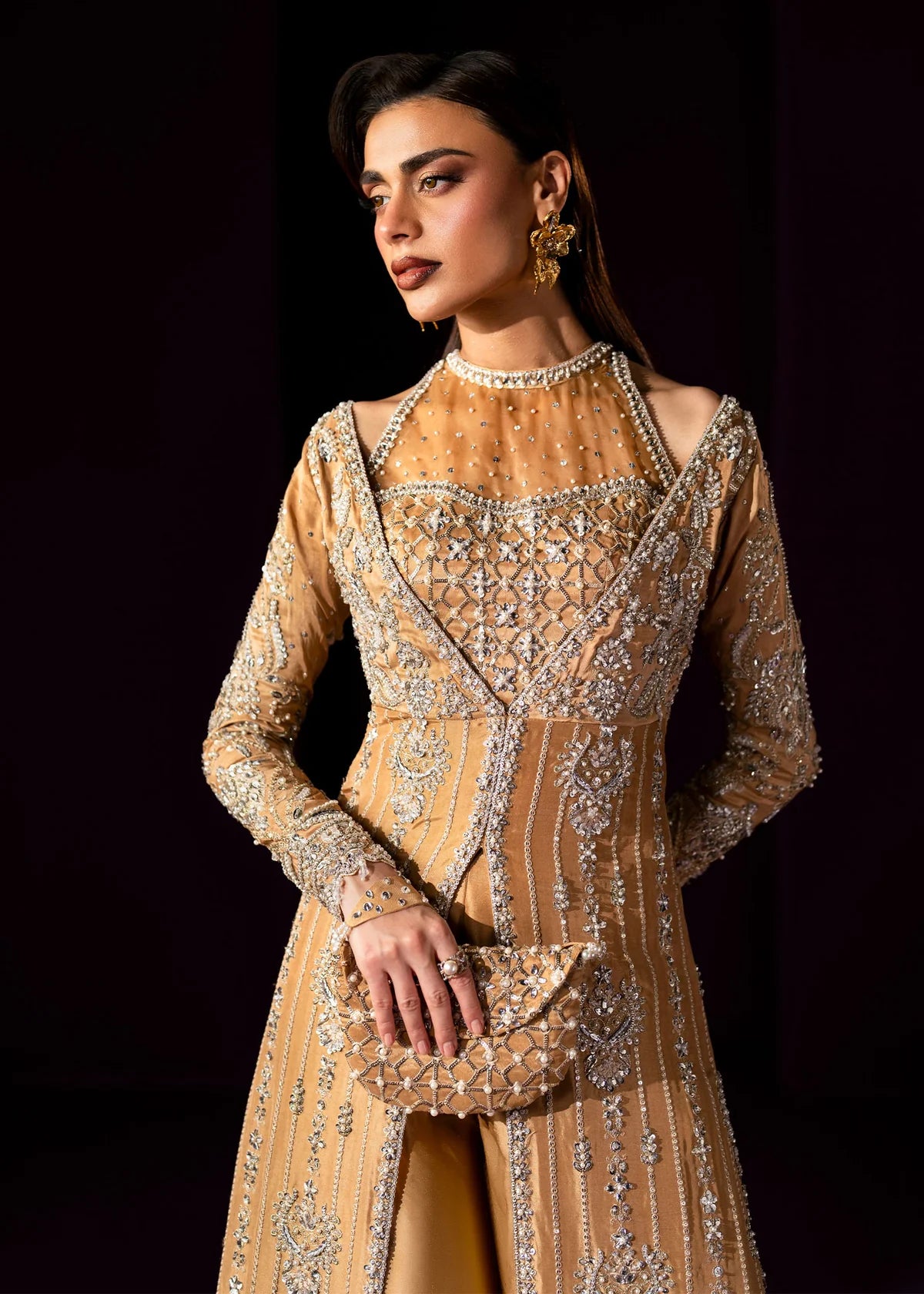 Oriana by Dastoor luxury couture formal outfit front view featuring nude gold tissue silk A-line gown with sheer halter bodice and structured neckline, heavily embellished with Swarovski crystals, pearls, sequins and fine hand embroidery arranged in elegant scattered constellation pattern, flowing silhouette with soft flare drape paired with matching palazzo pants in premium silk fabric, high-end designer outfit perfect for weddings, receptions, evening events and luxury formal occasions