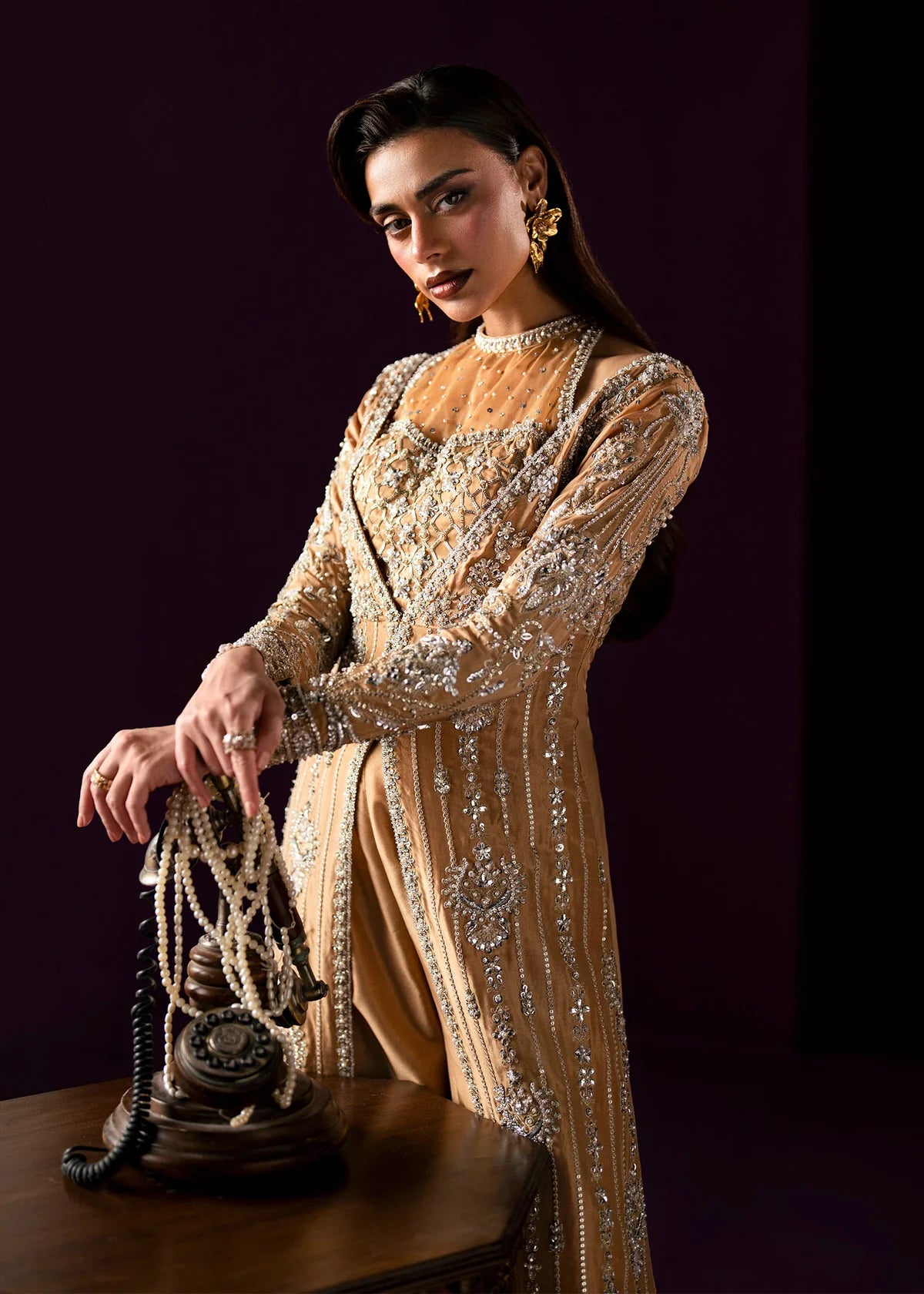 Oriana by Dastoor luxury couture formal outfit front view featuring nude gold tissue silk A-line gown with sheer halter bodice and structured neckline, heavily embellished with Swarovski crystals, pearls, sequins and fine hand embroidery arranged in elegant scattered constellation pattern, flowing silhouette with soft flare drape paired with matching palazzo pants in premium silk fabric, high-end designer outfit perfect for weddings, receptions, evening events and luxury formal occasions
