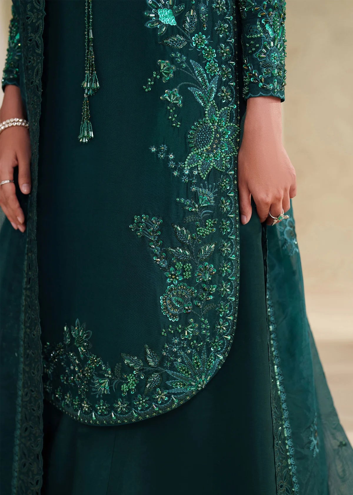 Eiza Dastoor luxury formal outfit front view featuring elegant ivory white raw silk shirt with heavy hand embroidery including intricate floral motifs, resham, sequins, kora and dabka embellishments arranged in refined symmetrical pattern, delicately detailed neckline and sleeve borders with fine craftsmanship, paired with matching straight trousers and soft organza dupatta with embroidered edges and light sequin spray, premium Pakistani designer outfit perfect for weddings, engagements, festive occasions 