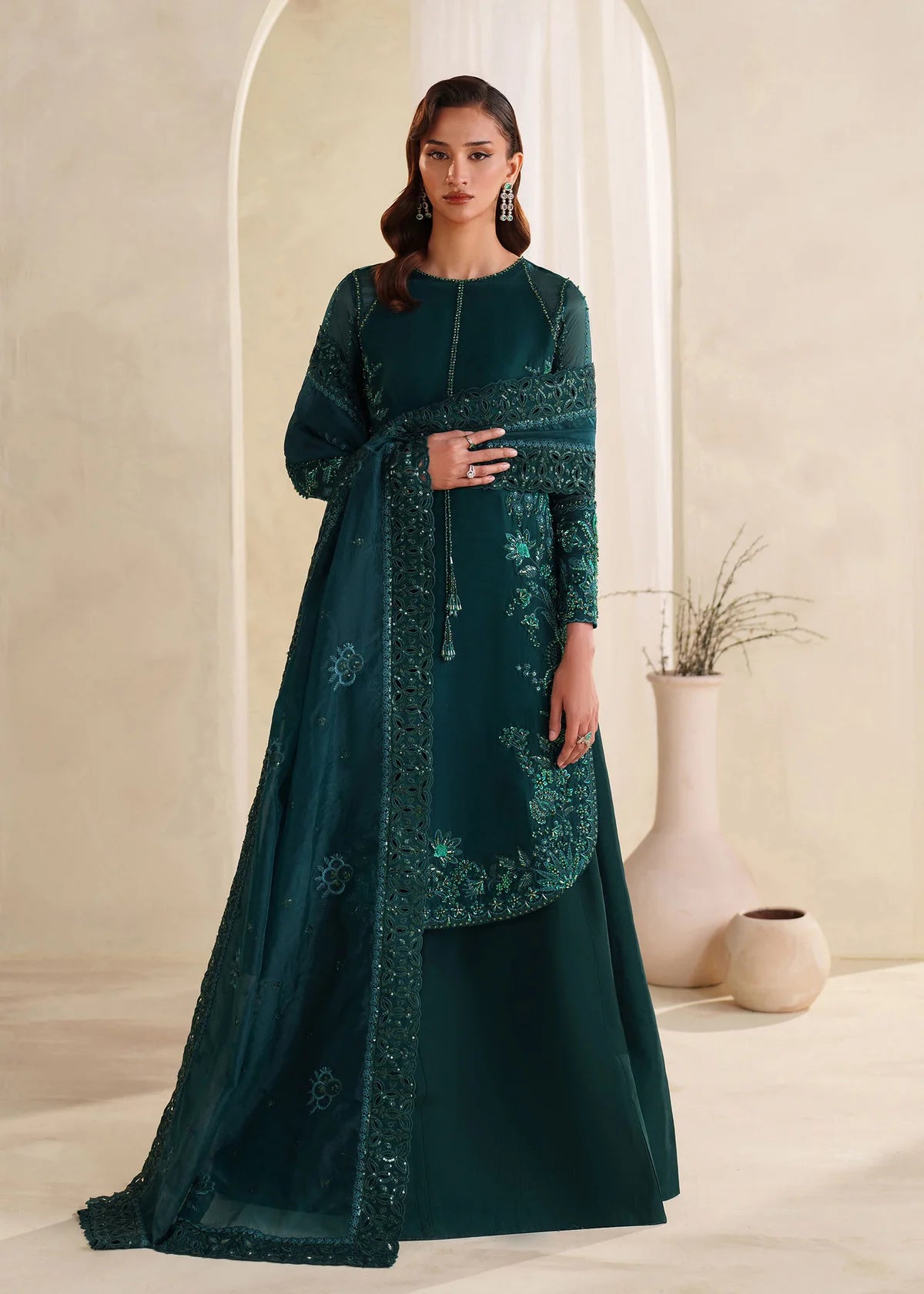 Eiza Dastoor luxury formal outfit front view featuring elegant ivory white raw silk shirt with heavy hand embroidery including intricate floral motifs, resham, sequins, kora and dabka embellishments arranged in refined symmetrical pattern, delicately detailed neckline and sleeve borders with fine craftsmanship, paired with matching straight trousers and soft organza dupatta with embroidered edges and light sequin spray, premium Pakistani designer outfit perfect for weddings, engagements, festive occasions 