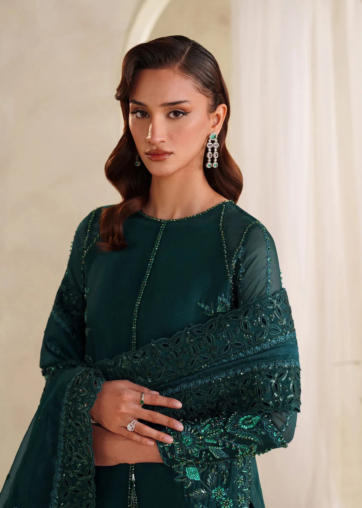 Eiza Dastoor luxury formal outfit front view featuring elegant ivory white raw silk shirt with heavy hand embroidery including intricate floral motifs, resham, sequins, kora and dabka embellishments arranged in refined symmetrical pattern, delicately detailed neckline and sleeve borders with fine craftsmanship, paired with matching straight trousers and soft organza dupatta with embroidered edges and light sequin spray, premium Pakistani designer outfit perfect for weddings, engagements, festive occasions 