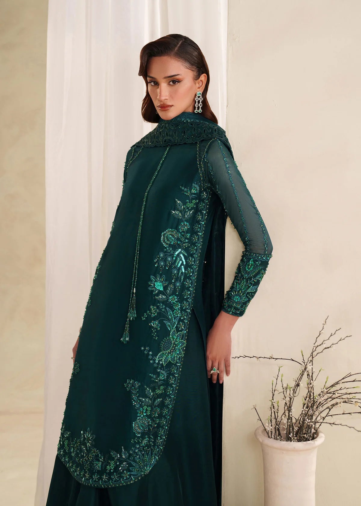 Eiza Dastoor luxury formal outfit front view featuring elegant ivory white raw silk shirt with heavy hand embroidery including intricate floral motifs, resham, sequins, kora and dabka embellishments arranged in refined symmetrical pattern, delicately detailed neckline and sleeve borders with fine craftsmanship, paired with matching straight trousers and soft organza dupatta with embroidered edges and light sequin spray, premium Pakistani designer outfit perfect for weddings, engagements, festive occasions 