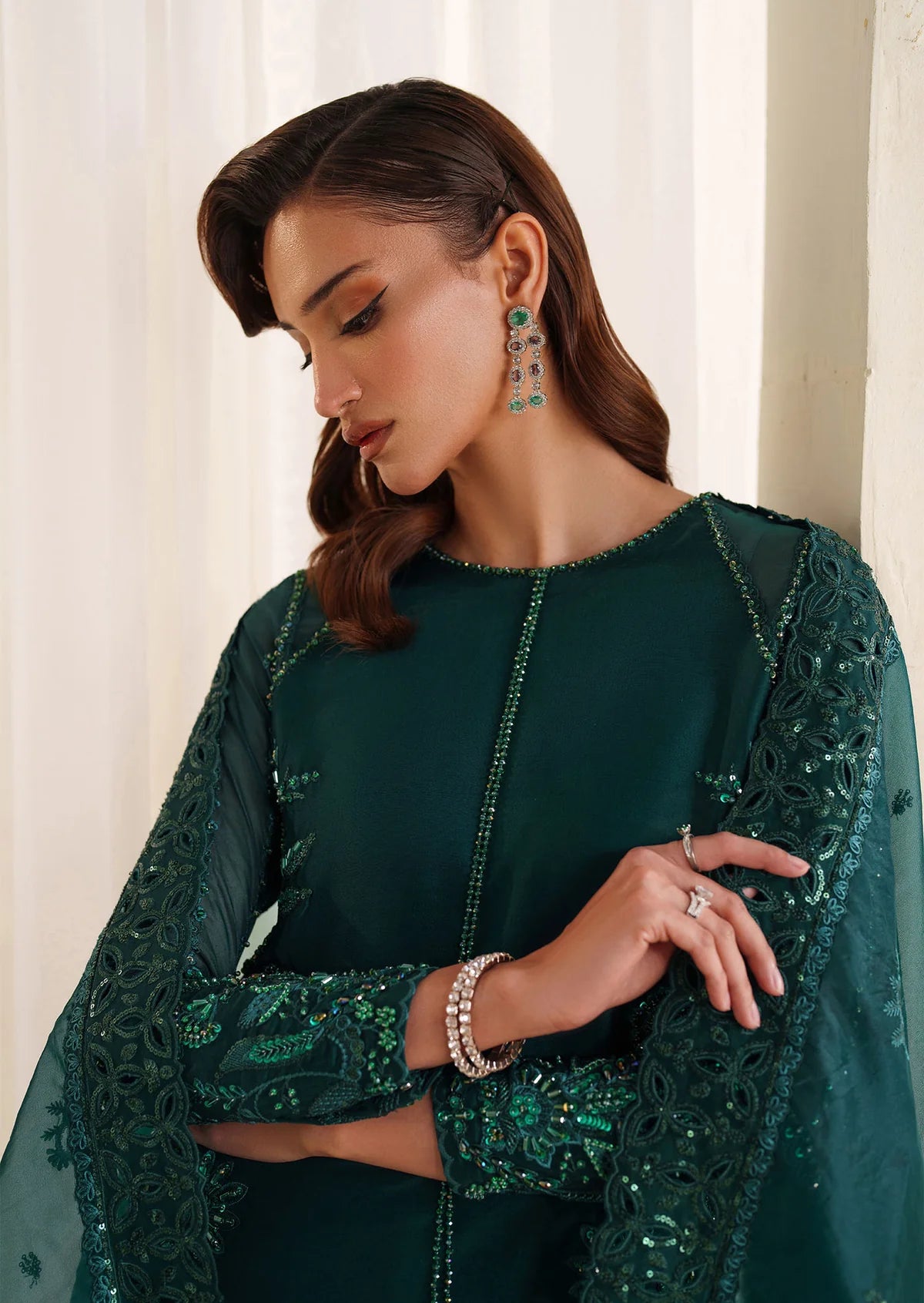 Eiza Dastoor luxury formal outfit front view featuring elegant ivory white raw silk shirt with heavy hand embroidery including intricate floral motifs, resham, sequins, kora and dabka embellishments arranged in refined symmetrical pattern, delicately detailed neckline and sleeve borders with fine craftsmanship, paired with matching straight trousers and soft organza dupatta with embroidered edges and light sequin spray, premium Pakistani designer outfit perfect for weddings, engagements, festive occasions 