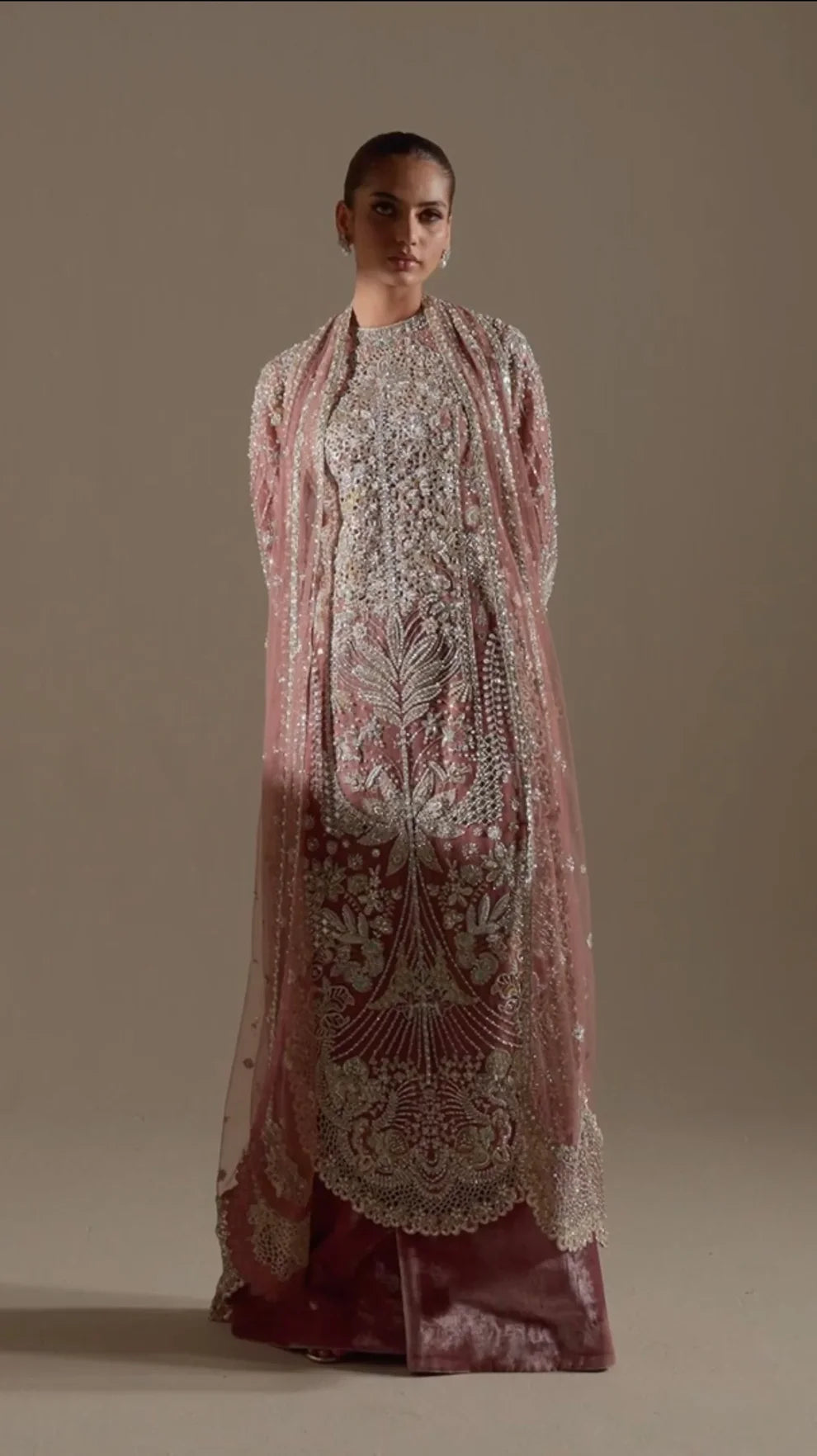 Velisse Soraya luxury dusty rose pink couture formal outfit front view featuring heavily hand-embellished organza shirt with intricate zari, naqshi, dabka, sequins and crystal embroidery arranged in royal symmetrical bridal pattern, richly detailed neckline and sleeves with fine resham work, paired with flowing lehenga/gharara in soft blush rose tone and heavily embroidered organza dupatta with scalloped borders, antique gold finishing and mukaish spray, premium designer wedding dress.