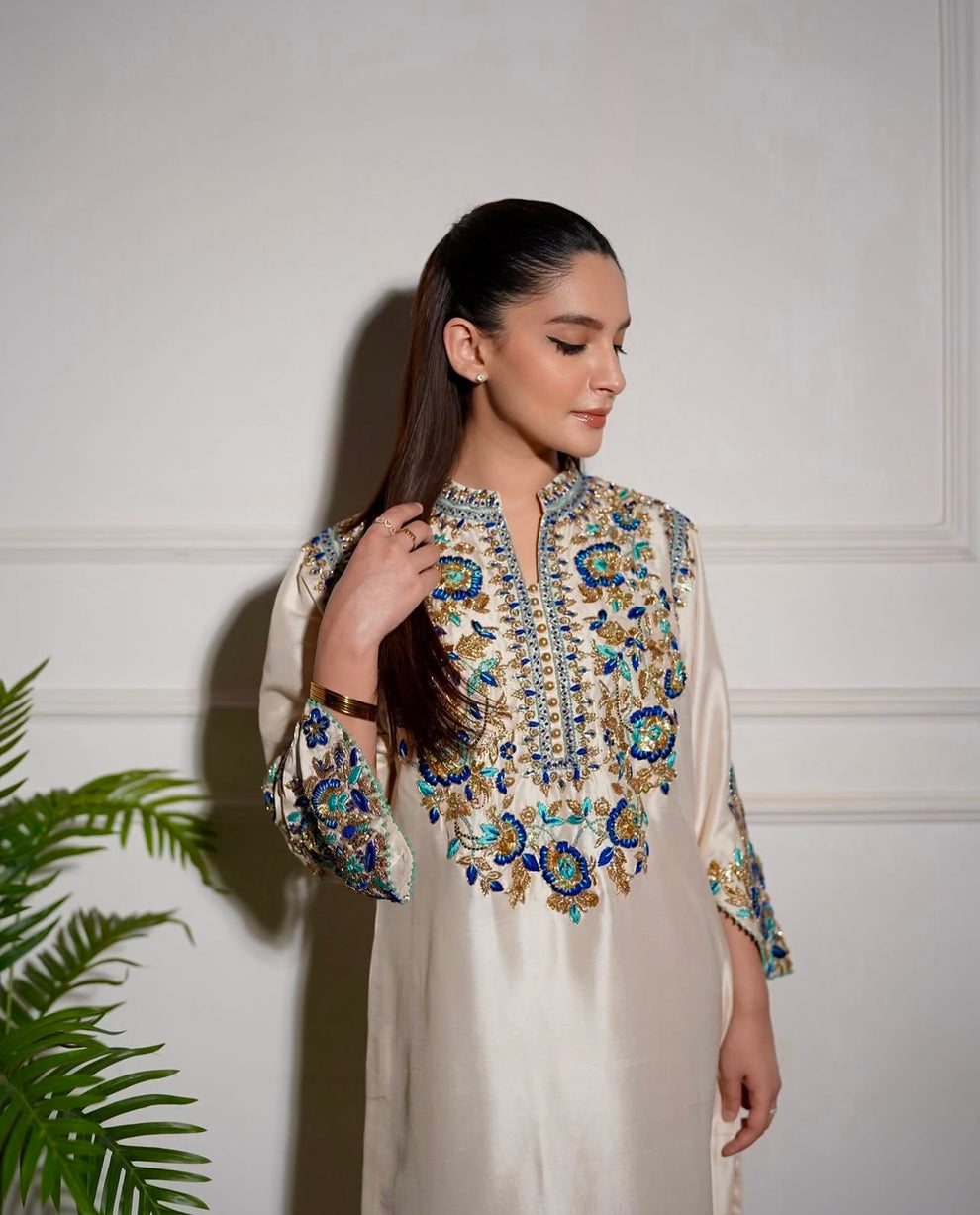 Elegant white designer embroidered suit with trousers
Premium Aleena Khan formal ensemble detailed embroidery close up
Aleena Khan white festive outfit full look for women