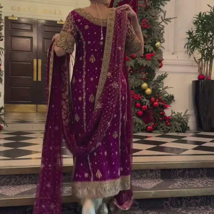 Libah by Haris Shakeel luxury formal outfit front view featuring deep maroon raw silk shirt with heavy all-over gold hand embroidery including intricate floral motifs, zari, resham and sequins work, elegant straight silhouette with richly decorated sleeves and ornate border finishing, paired with champagne toned straight trousers and sheer organza dupatta with subtle booti spray and detailed embroidered pallu, premium Pakistani designer outfit perfect for weddings, festive occasions, mehndi.