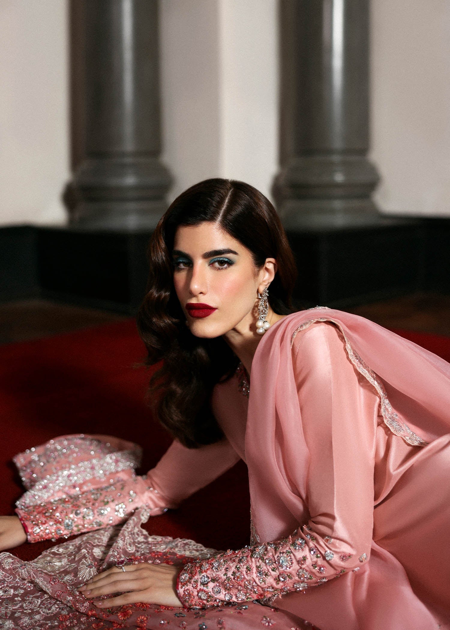 Side view of model lying on floor wearing Hussain Rehar Evara blush pink embroidered suit with elegant silhouette