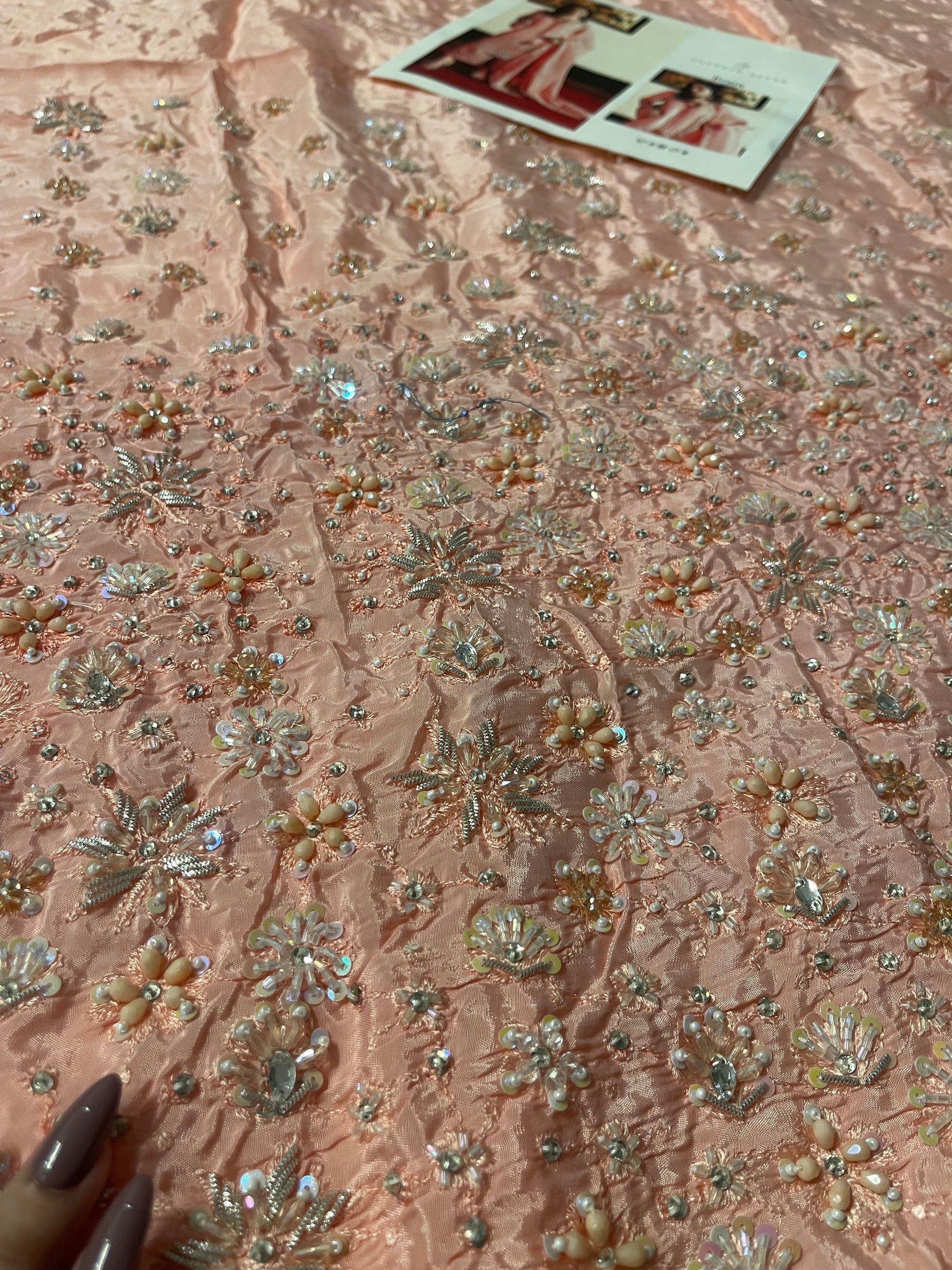 Closeup of unstitched Hussain Rehar Evara shirt fabric highlighting intricate floral embroidery and sequin work on blush pink raw silk