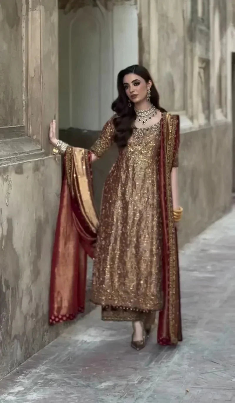 Meerub by Haris Shakeel luxury formal outfit front view featuring deep bronze raw silk shirt with intricate all-over gold hand embroidery, delicate floral motifs, zari and resham threadwork with refined sequin accents, elegantly structured straight silhouette with richly embellished neckline and sleeve borders, paired with matching straight trousers and beautifully coordinated dupatta with embroidered pallu and subtle maroon piping, premium Pakistani designer outfit perfect for weddings, mehndi, baraat etc
