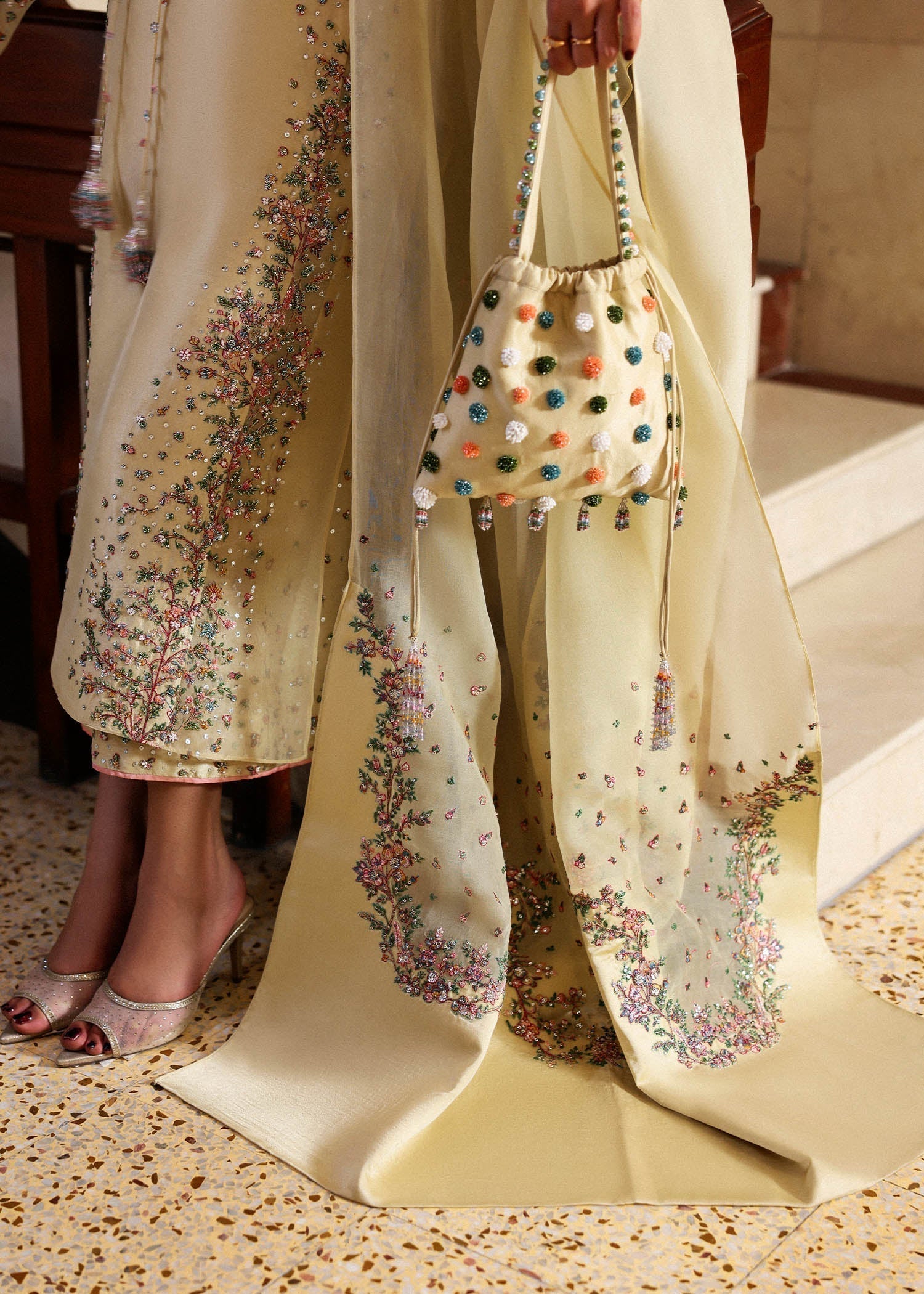 Detailed left side close up of organza dupatta and daaman embroidery on butter yellow outfit