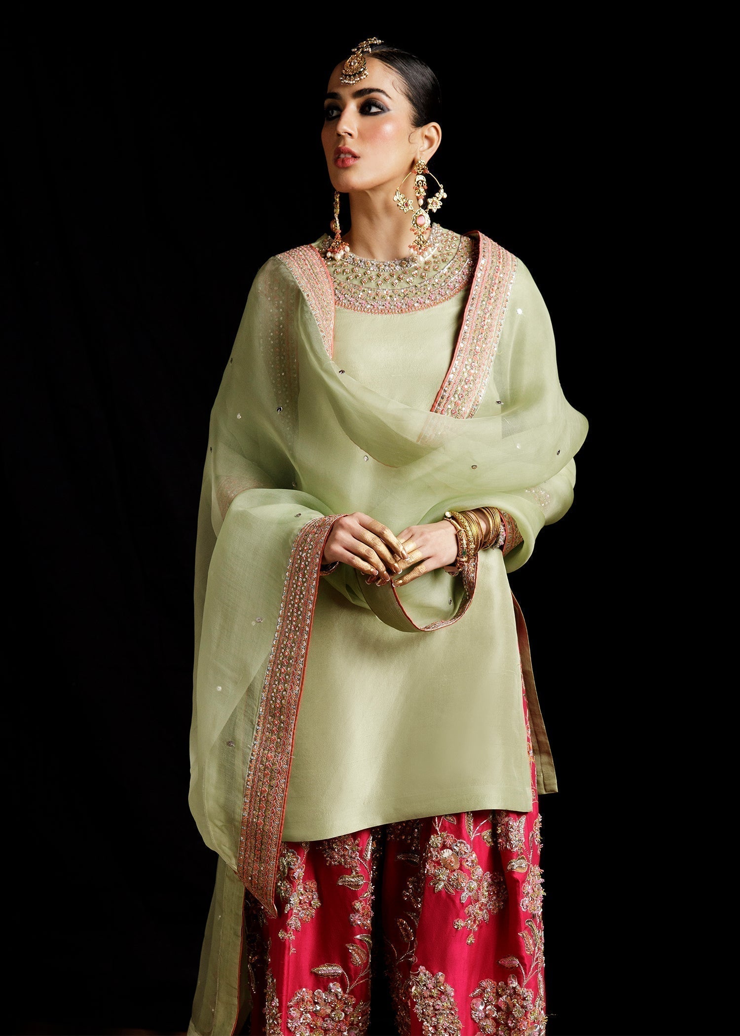 Model wearing pistachio green embroidered Pakistani formal outfit with contrast shalwar