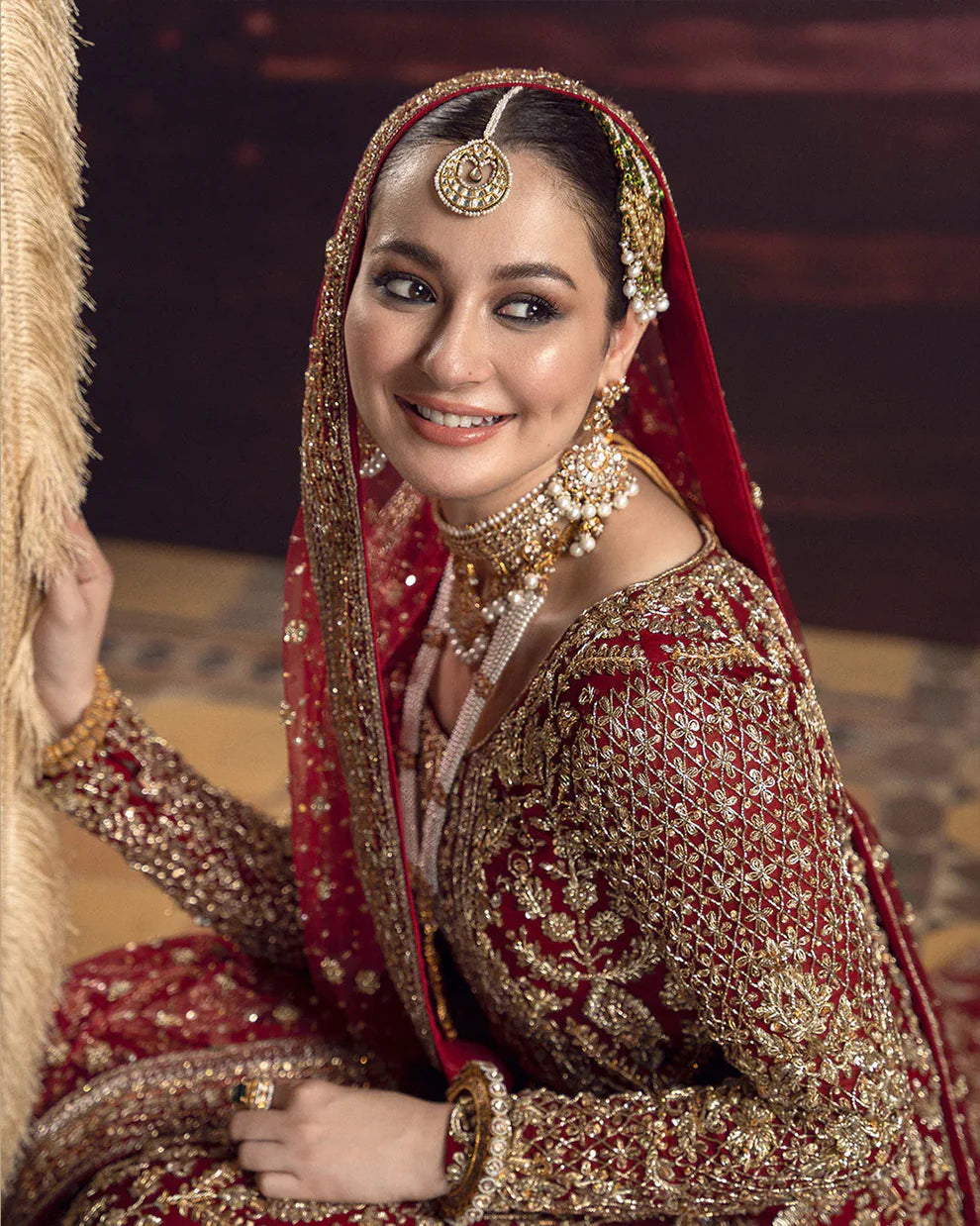 Roushana Faiza Saqlain luxury red bridal couture outfit front view featuring heavily hand-embellished chiffon pishwas with intricate dabka, marori, resham and zardozi embroidery forming traditional floral and vine motifs, richly detailed neckline and sleeves with full handwork, paired with Korean raw silk gharara with fine embellishment and flowing net dupatta adorned with heavy embroidery and ornate border finishing, premium bridal wedding dress perfect for brides, receptions and luxury festive occasions